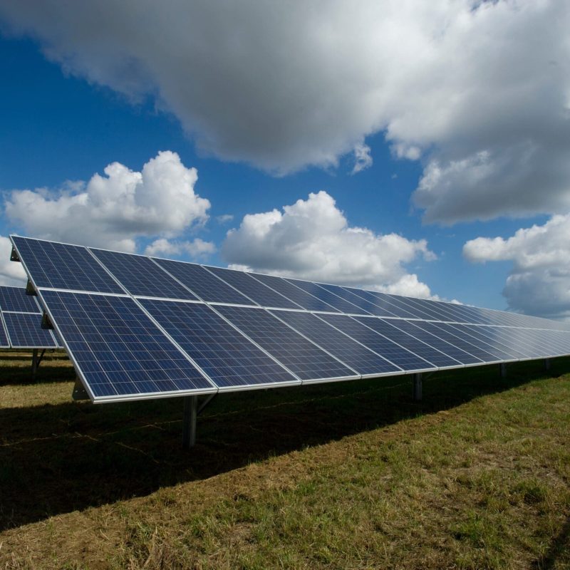 Solar panels under a cloudy sky in an open field, showcasing renewable energy solutions.