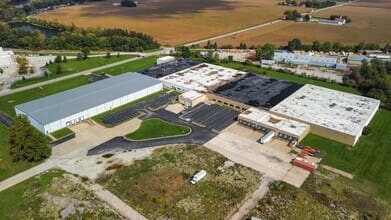 Aerial view of a manufacturing facility in a rural setting, highlighting its large warehouses and surrounding fields.