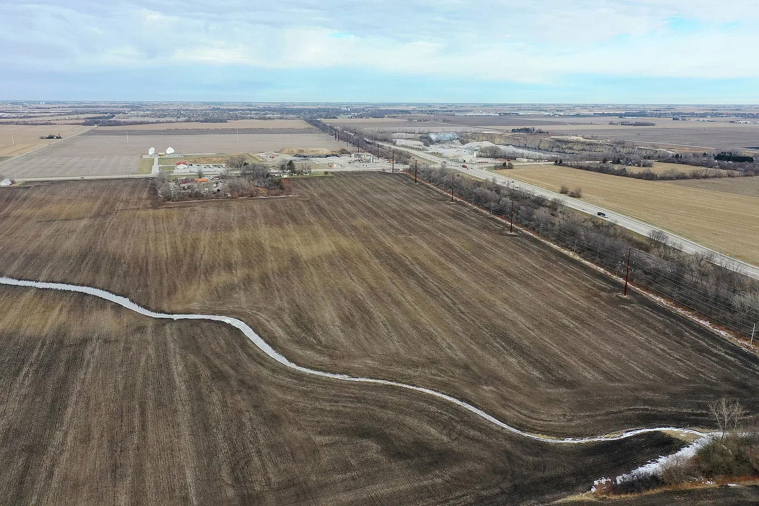 Aerial view of vast fields and distant infrastructure.