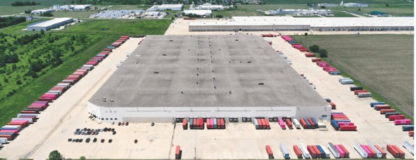 Large industrial warehouse with trucks lined up outside, showcasing distribution capability.